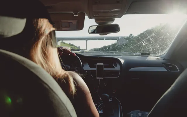 Pessoa dirigindo um automóvel em uma estrada.
