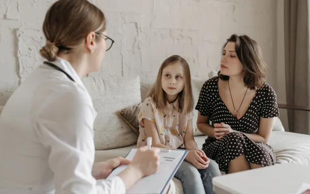 Profissional de saúde conversando com uma mãe e sua filha.